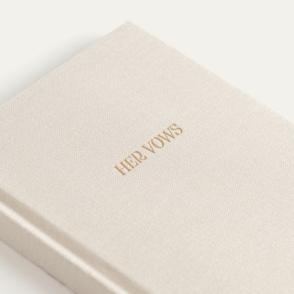 Close-up of the ivory linen vow book cover with HER VOWS in gold foil