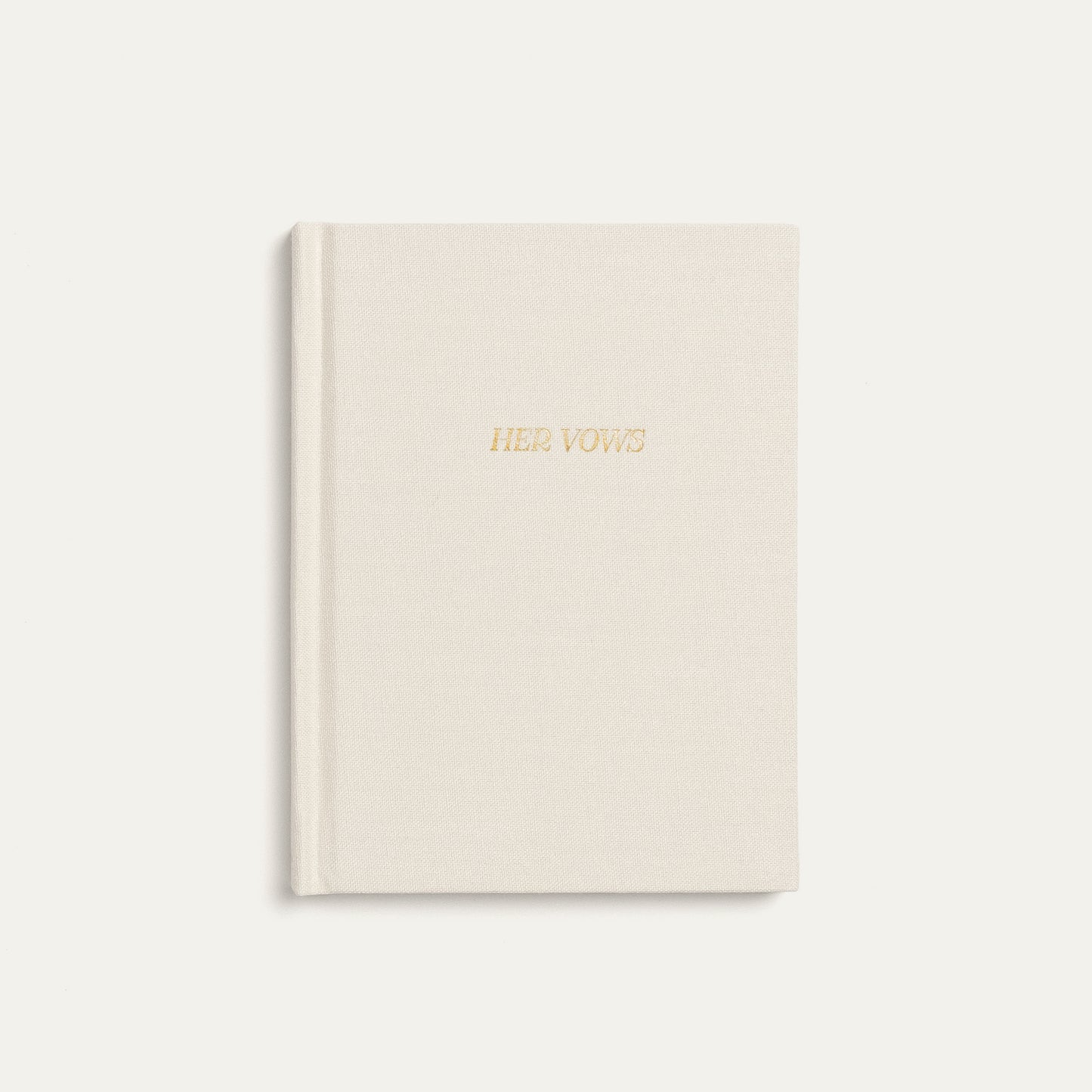 A cream-colored hardcover vow book with 'HER VOWS' embossed in gold foil on the front cover, set against a matching cream background.