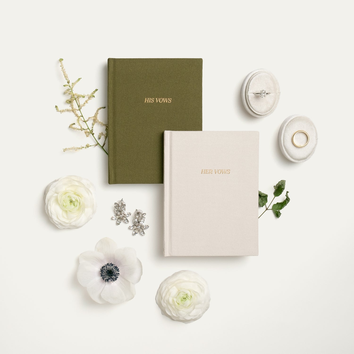 Two Wildflower Paper Goods vow books, one green and one white, with gold foil lettering.